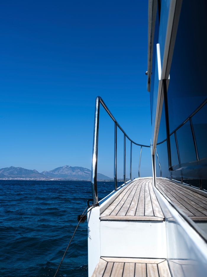 team-04 Scenic view from a yacht deck overlooking the ocean and distant mountains under a clear blue sky.