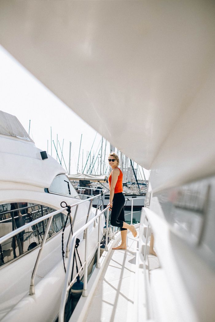 who-we-are A woman stands on a yacht on a sunny summer day, enjoying leisure time.