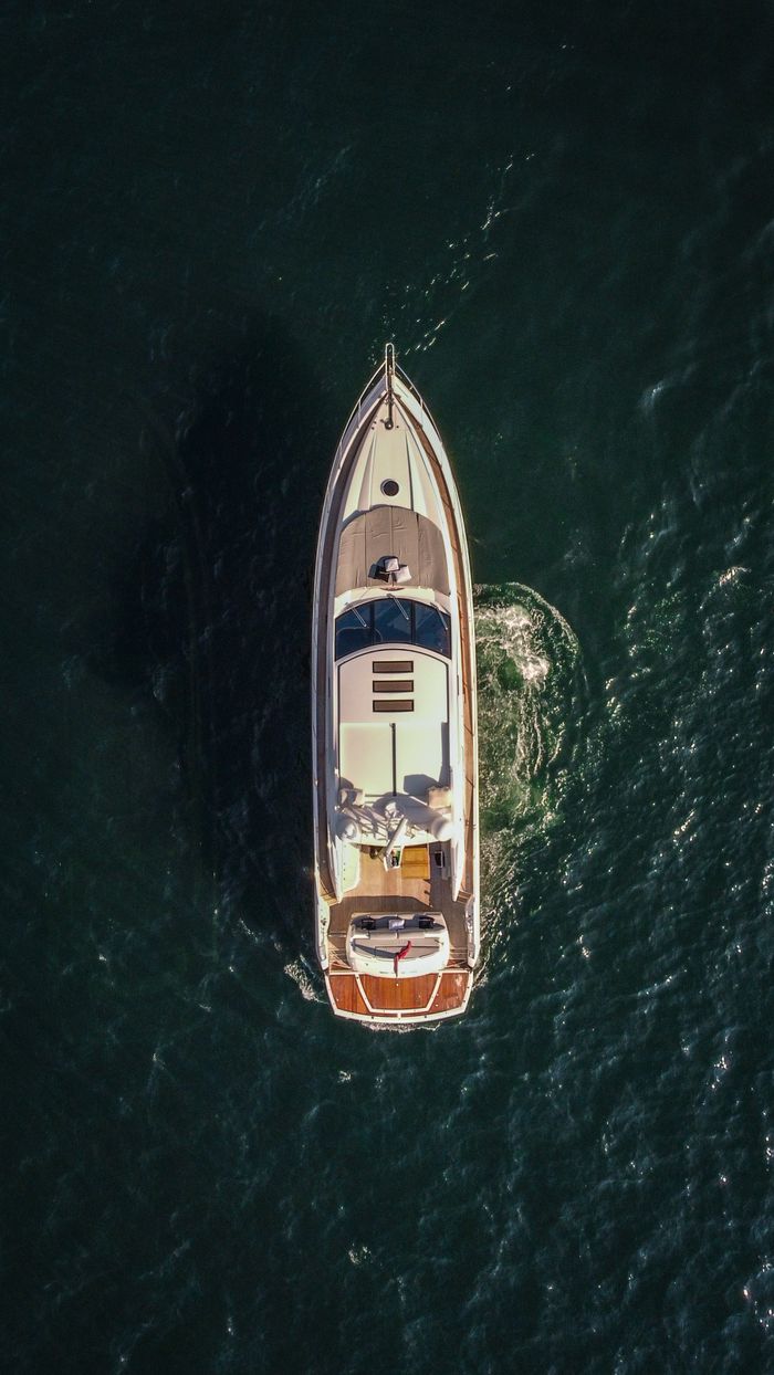 services-04 An aerial shot of a luxury yacht cruising through calm sea waters, showcasing opulence and adventure.